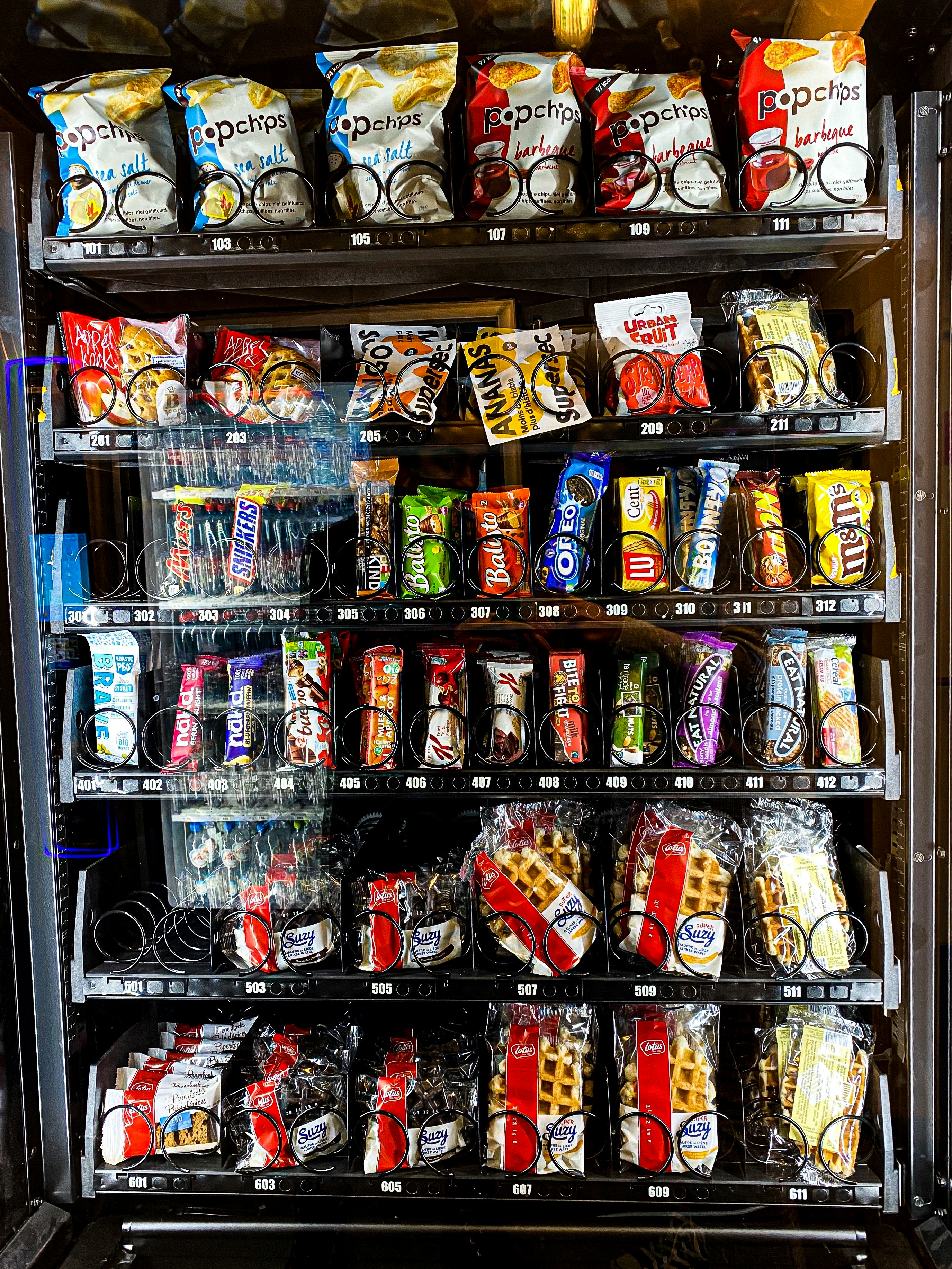 diverse vending machine products, snacks and drinks, neon pink lighting, modern display, clean arrangement